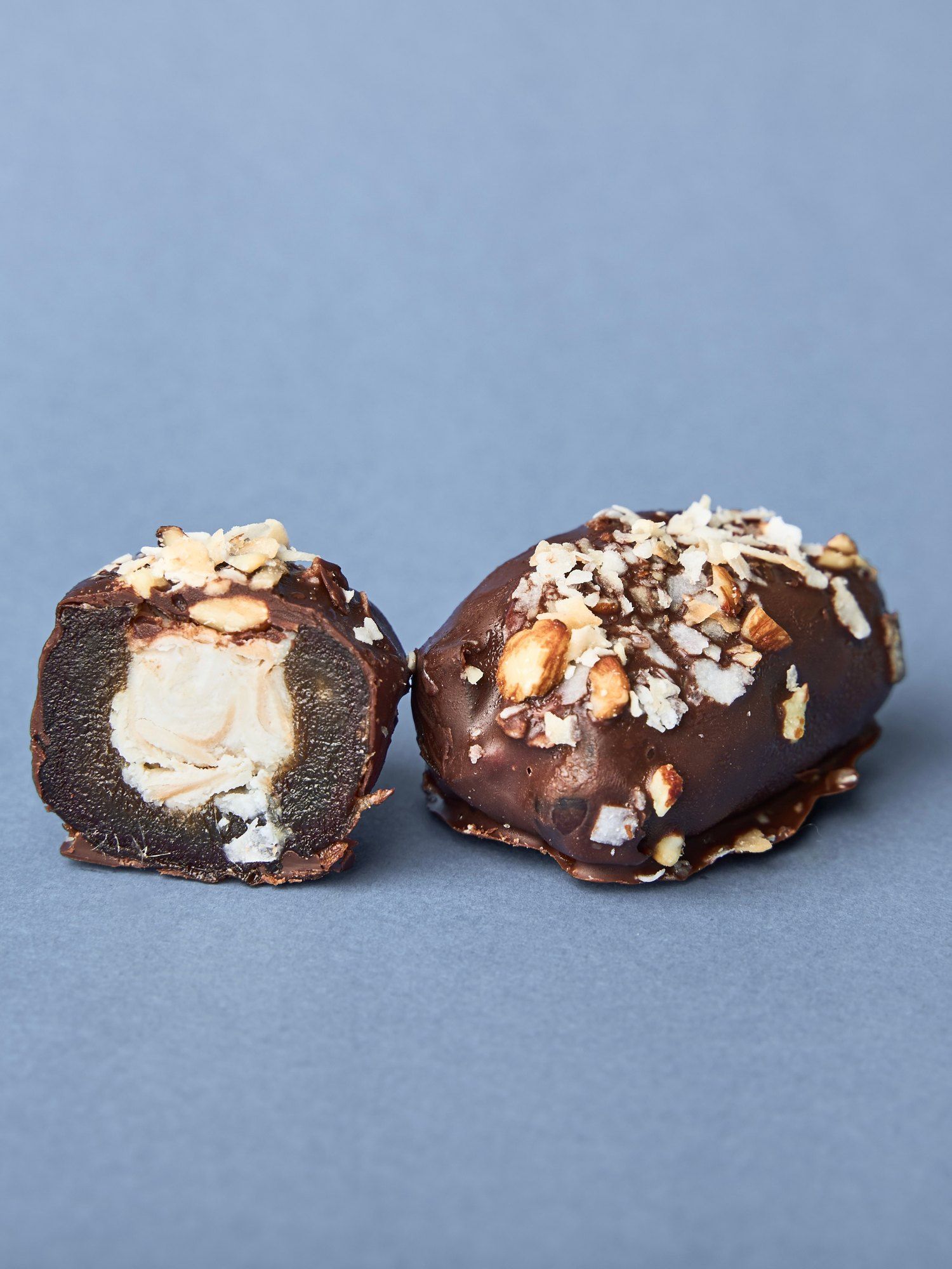 A PITT Coconut date split open beside a whole one, the coconut cream filling visible
